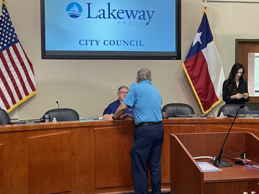 Man standing at a city council dais.