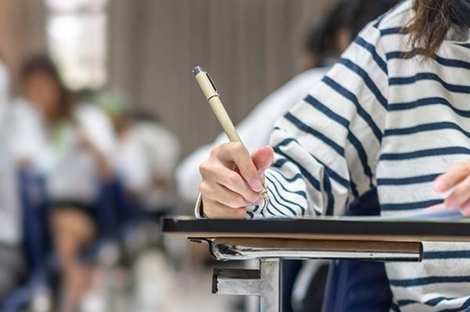 Stock photo of a student sitting at a desk and writing with a pen