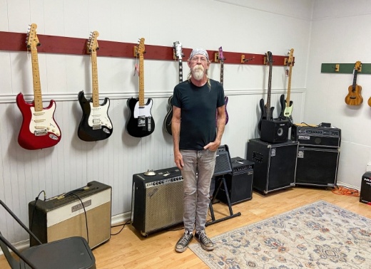 JAMS Music owner Ace Pepper stands in front of some of the guitars and amplifiers for sale in the guitar room. 