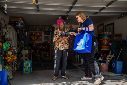 Jillian Huskin delivers a meal to Mamie Schatz's garage, surrounded by dozens of unfinished painting projects that will eventually take their place in her colorful front yard. Credit: Kaylee Greenlee Beal 2022