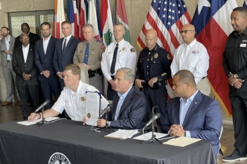 Texas Gov. Greg Abbott displays a signed storm disaster declaration during a news conference at Dallas City Hall.