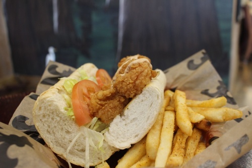The shrimp po’boy ($12.50) features fried shrimp dressed with mayo, lettuce, tomatoes and house remoulade served with fries. (Kayli Thompson/Community Impact Newspaper)