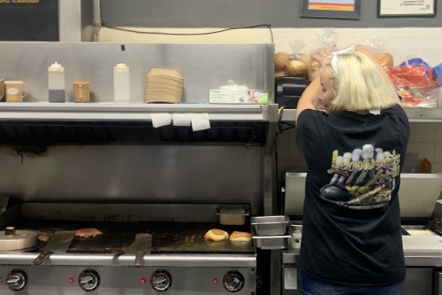 Photo of a woman with short blonde hair preparing a burger in a kitchen