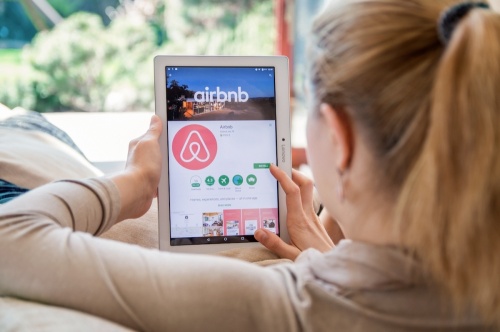 Photo of a woman looking at the Airbnb app on a tablet