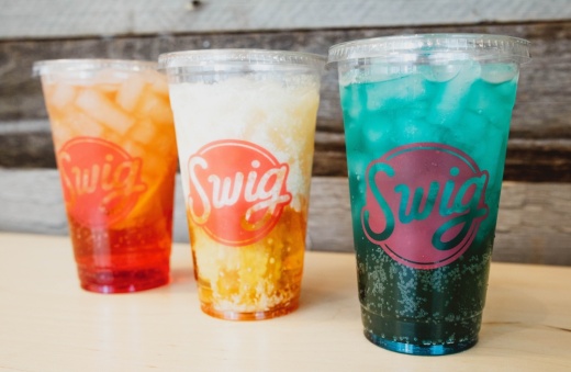Three Swig drinks of varying colors in a line with the logo visible on each cup.