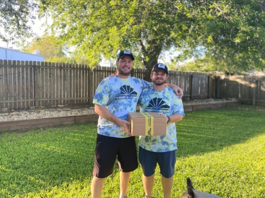 Two men standing side by side and holding a box.