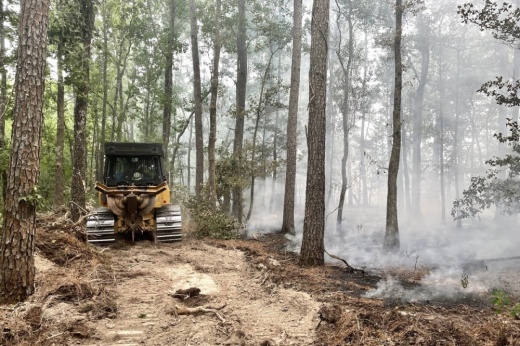 A tractor clears trees during a wildfire