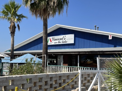Front of a blue building with two palm trees.