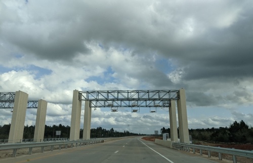 Four pale pillers with a metallic support for toll road readers, against a cloudy background
