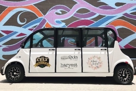 A McKinney DASH shuttle car in front of a rainbow wavy line mural