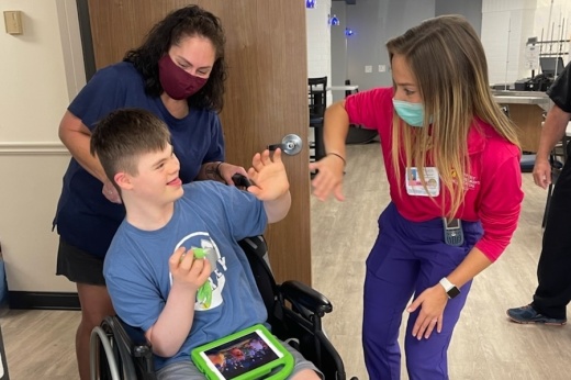 Stephanie Barnett  (left) and Silas Eli Barnett (center), her 14-year-old Johnson High School freshman son, enjoy a special moment with Hallie Rhoads, Baptist Children’s Hospital certified Child Life specialist, in an Aug. 18 celebration of the 25th anniversary of Baptist Children’s Hospital at North Central. Rhoads and fellow Child Life specialists have helped young patients such as Silas Barnett to lower their anxiety and think positively about their hospital experience. (Courtesy Baptist Health System)