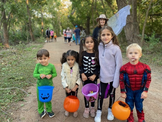 Children in Halloween costumes holding candy buckets. 