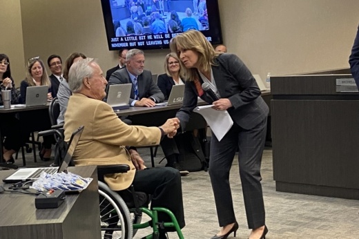 Woman shakes man's hand at meeting in front of staff