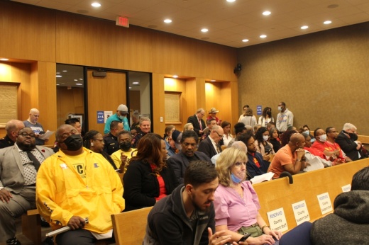 People fill the wooden benches in the Commissioners Court courtroom.