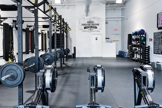 Interior of gym with rowing machines and weight lifting racks.