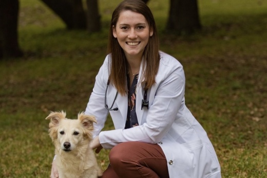 Woman in a white coat sitting with a dog