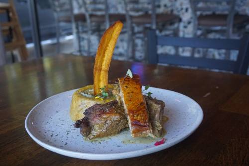 Slow-roasted pork shoulder is served with mofongo, which consists of mashed plantains, garlic and pork belly. (Mikah Boyd/Community Impact)