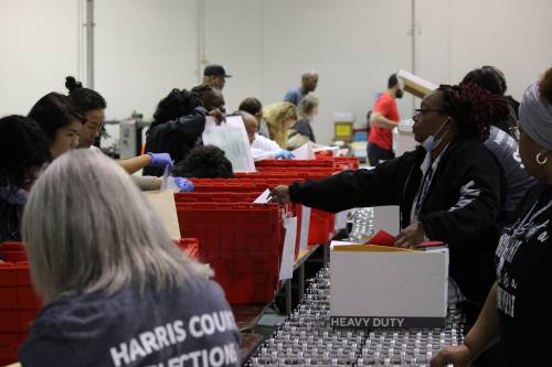 Two lines of election workers sort through boxes of election materials.