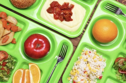 Three green trays with school lunches on them.