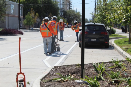 Workers in Midtown put down new lane markings on Caroline Street. (Shawn Arrajj/Community Impact)