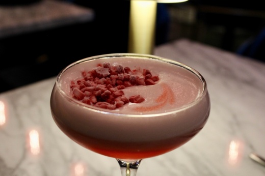 The Raspberry Beret ($18) cocktail includes vodka, raspberry liqueur, lemon juice, orgeat, muddled raspberries and egg white. (Shelbie Hamilton/Community Impact)