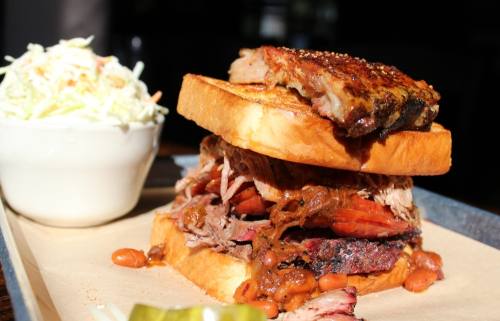 El Jefe ($15) comes with brisket, pulled pork, sausage and barbecue beans served between slices of Texas toast and topped with a spare rib. This menu item is pictured with pineapple coleslaw ($3). (Karen Chaney/Community Impact)