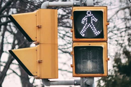 A yellow traffic signal with a white walk sign illuminated.