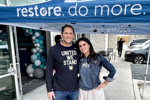 A couple posing for a picture in front of a canopy tent.