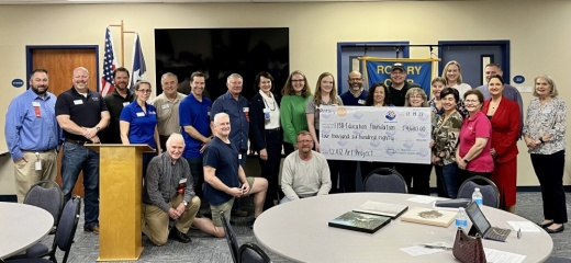 Group of adults stand holding large check