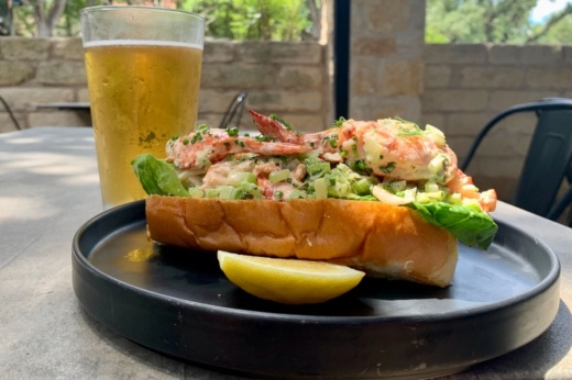 Lobster roll on a plate with a glass of beer.