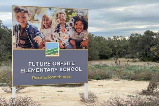 sign on a plot of land reading "future on-site elementary school" with photo of multiple children blowing bubbles