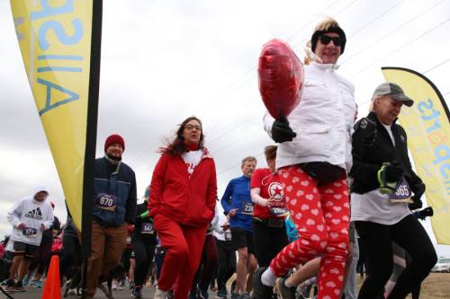 runner holds red heart balloon wearing valentines day pants 