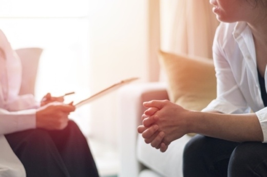 Doctor with clipboard speaks with seated patient