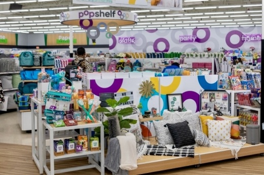 Sofa with pillows and a side table with items for sale.