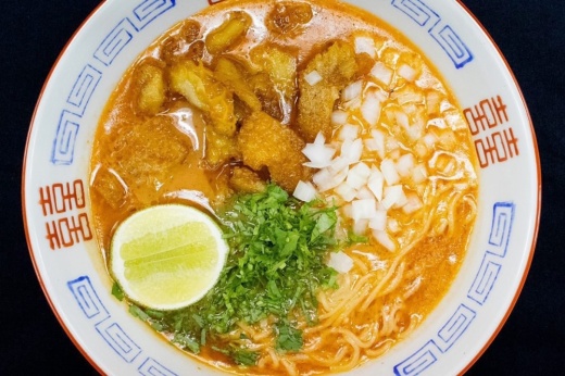 Lemon, cilantro, noodles and meat in a bowl of soup