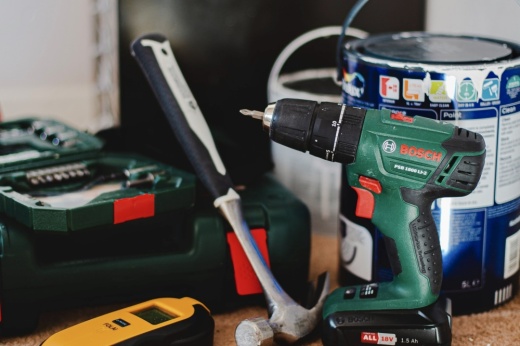 Some tools and paint on a wooden table.