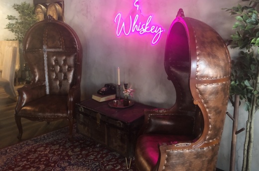 Inside Bosscat Kitchen are large chairs and a neon sign.