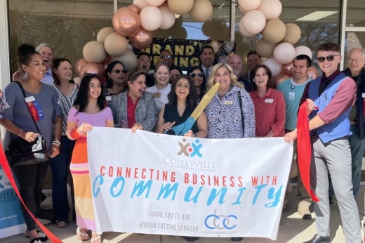 a group of people stand behind a banner as they cut a ribbon to celebrate the opening of a business