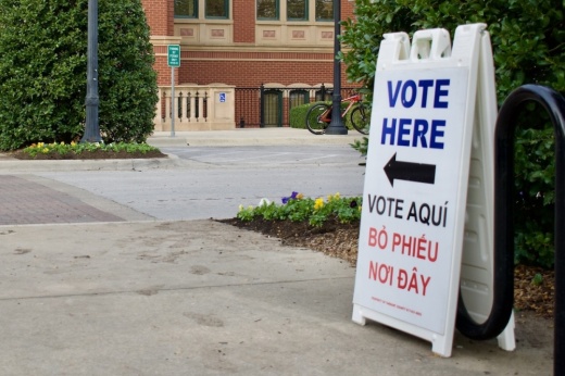 a white sign that says Vote Here points to a voting location