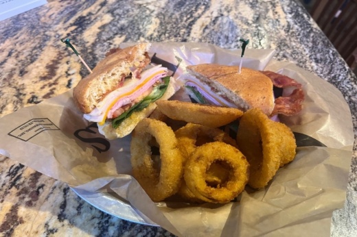 Tavern Club sandwich is piled high with bacon, ham, turkey, lettuce, tomatoes, onions and cheese.