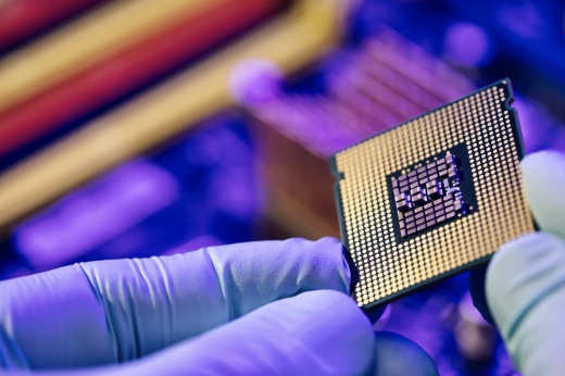 A person wearing gloves holds a semiconductor chip.