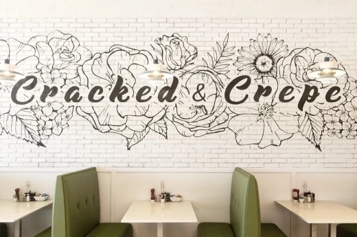 The inside of a restaurant with green booths and tables.