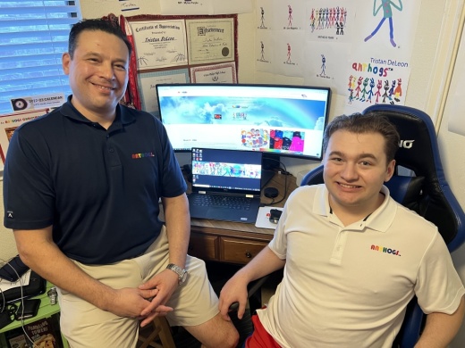tristan and his father alex smile in front of a computer monitor