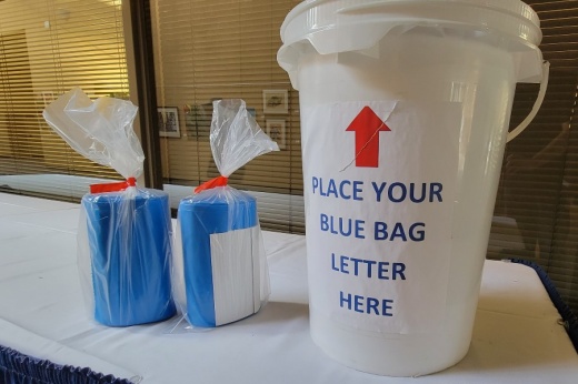 Blue recycling bag rolls next to receptacle