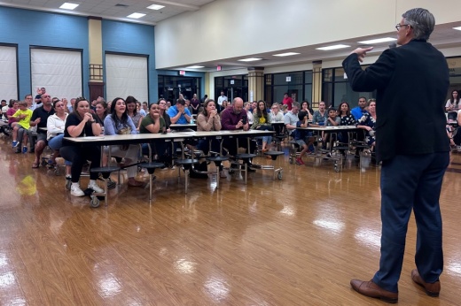 Board President Lee McLeod speaks to a room full of community members.