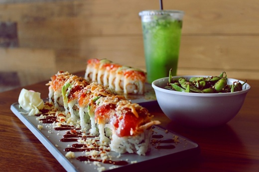 Sushi plate with a drink in the background.