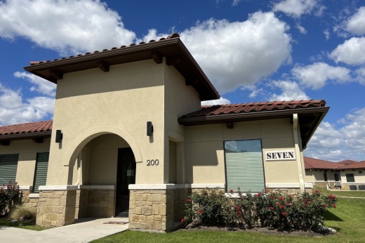 tan and brown building with blue sky and clouds in background