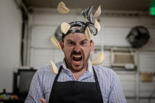 white man tossing up potato dumplings with intense expression