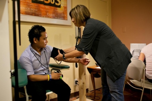 female nurse takes blood pressure of male patient