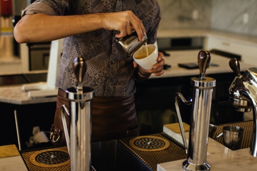 A barista pouring latte art into a mug
